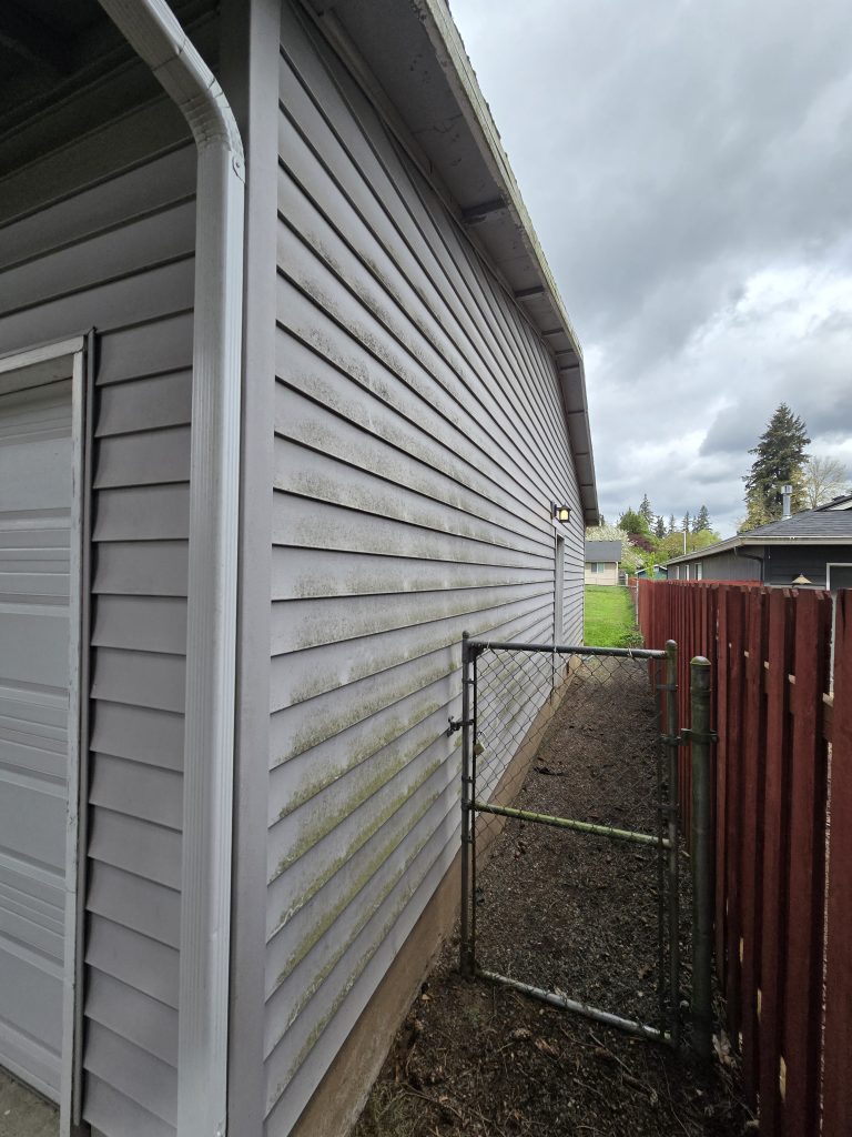 Gray siding house with red fence and gate.